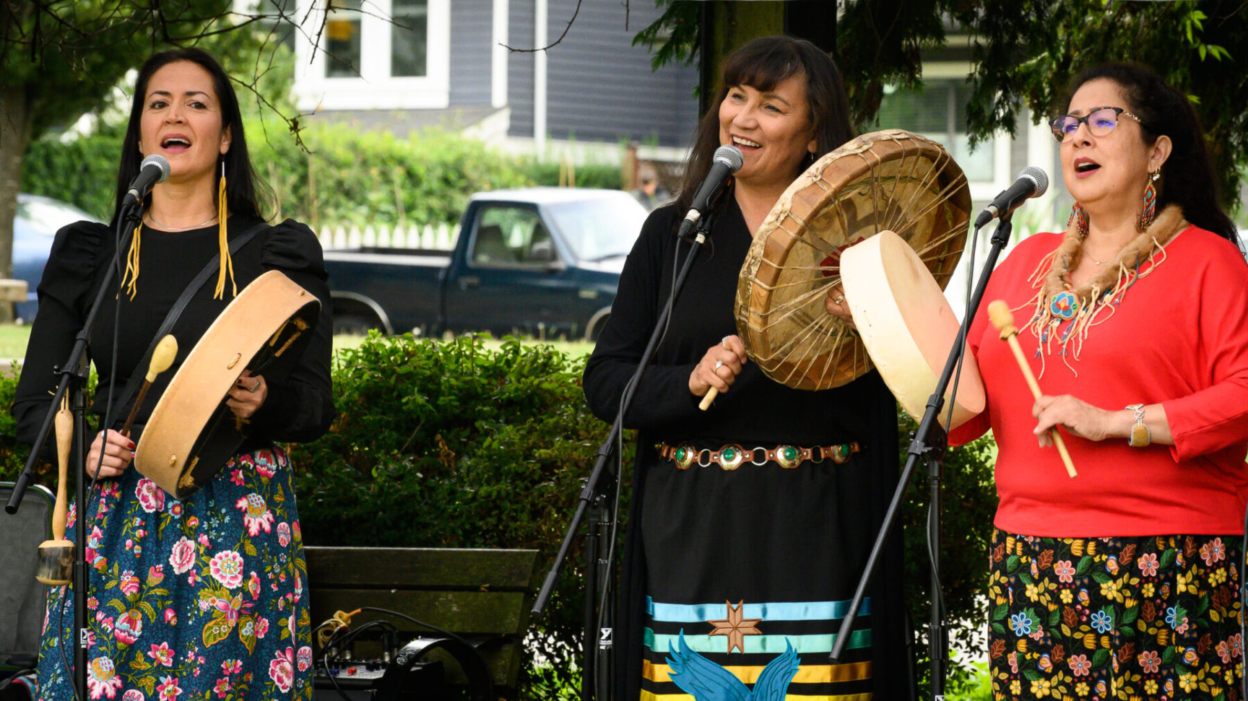 M'Girl performing with hand drums, standing in front of microphones.