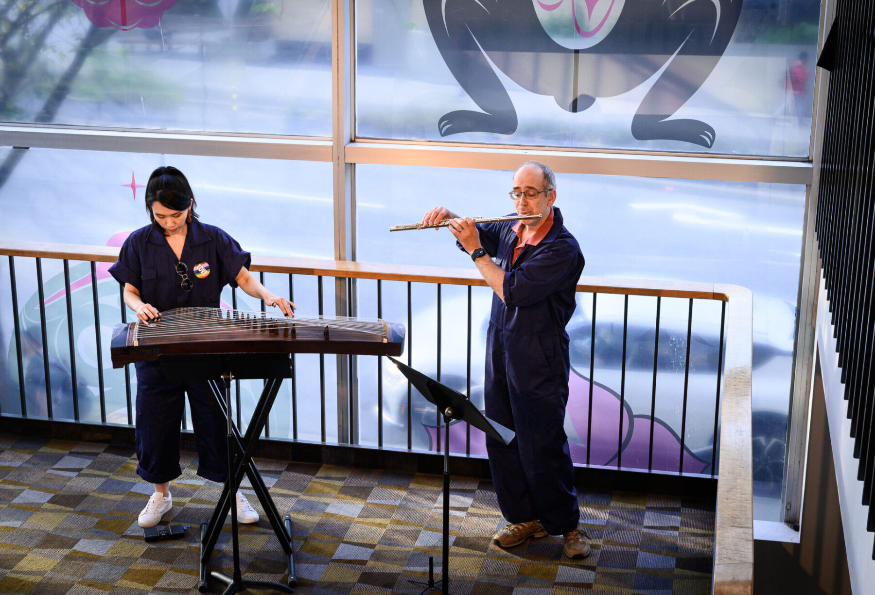 Dailin Hsieh playing the zheng and Paolo Bortolussi playing the flute, standing on the stair landing in the Playhouse lobby.